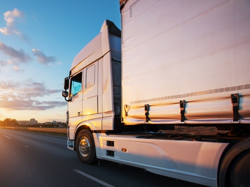 An Australian truck with proper load restraint equipment (truck side curtains) on a road.