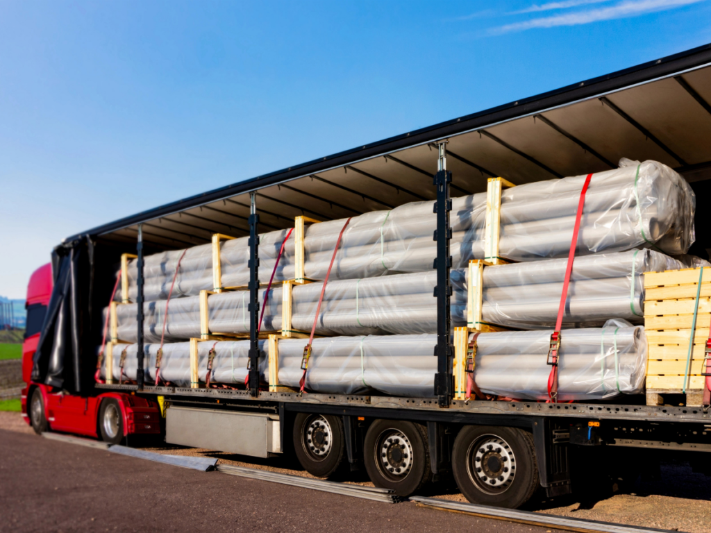 Tautliner truck with side curtain open carrying secured freight.