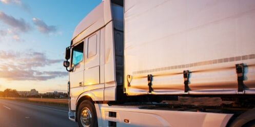 An Australian truck with proper load restraint equipment (truck side curtains) on a road.